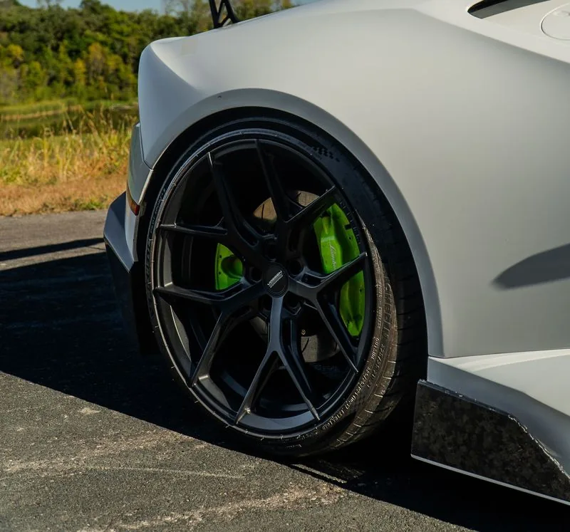 Black wheel with green brake calipers on a white car