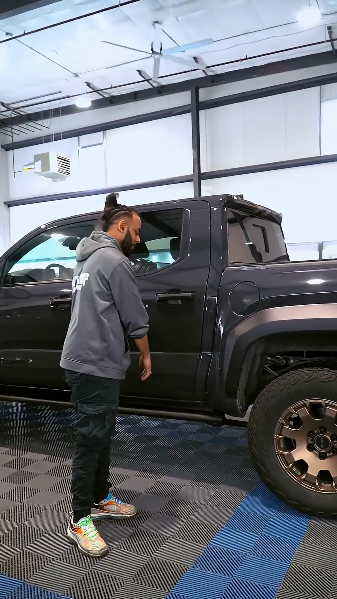 Installer standing beside a dark pickup in the shop
