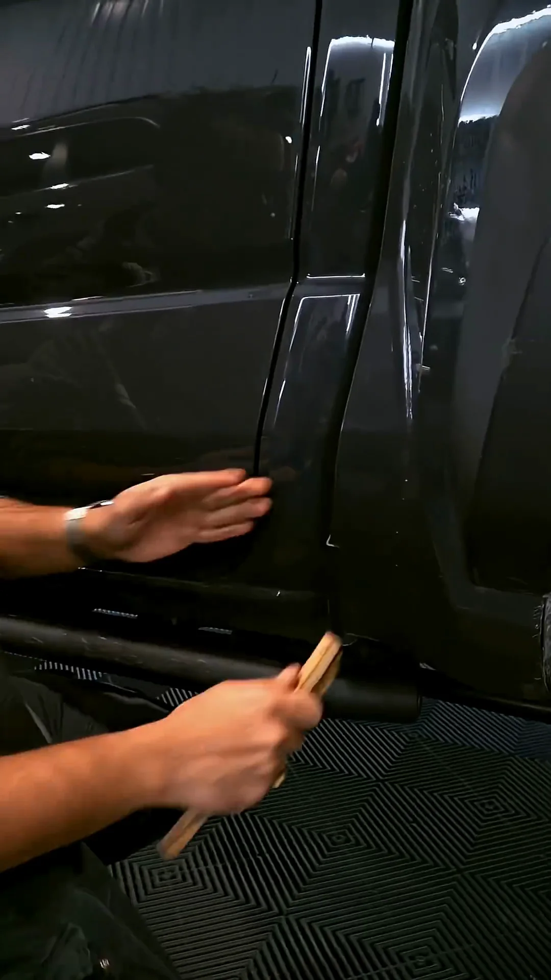 Hands working along the door edge of a dark pickup