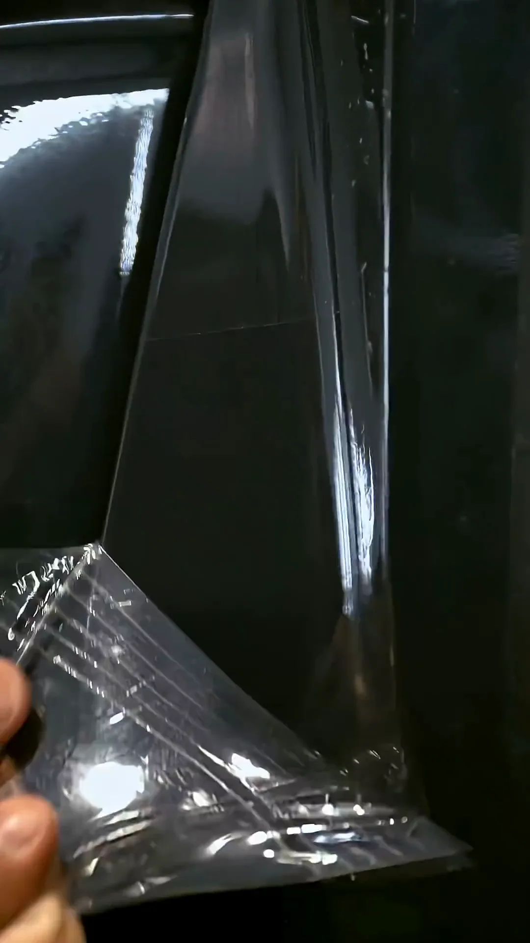 Hand holding a cut piece of clear paint protection film