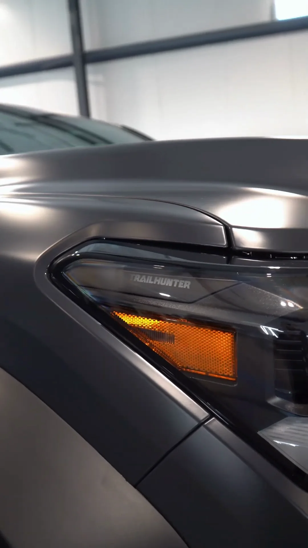 Headlight and fender of a matte gray Toyota Tacoma