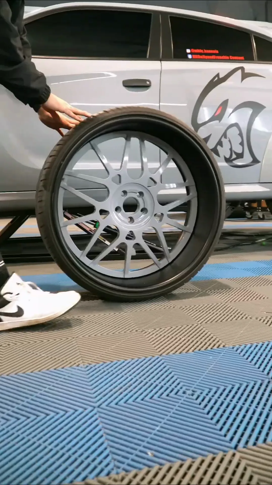 Technician rolling a new silver wheel across the shop floor