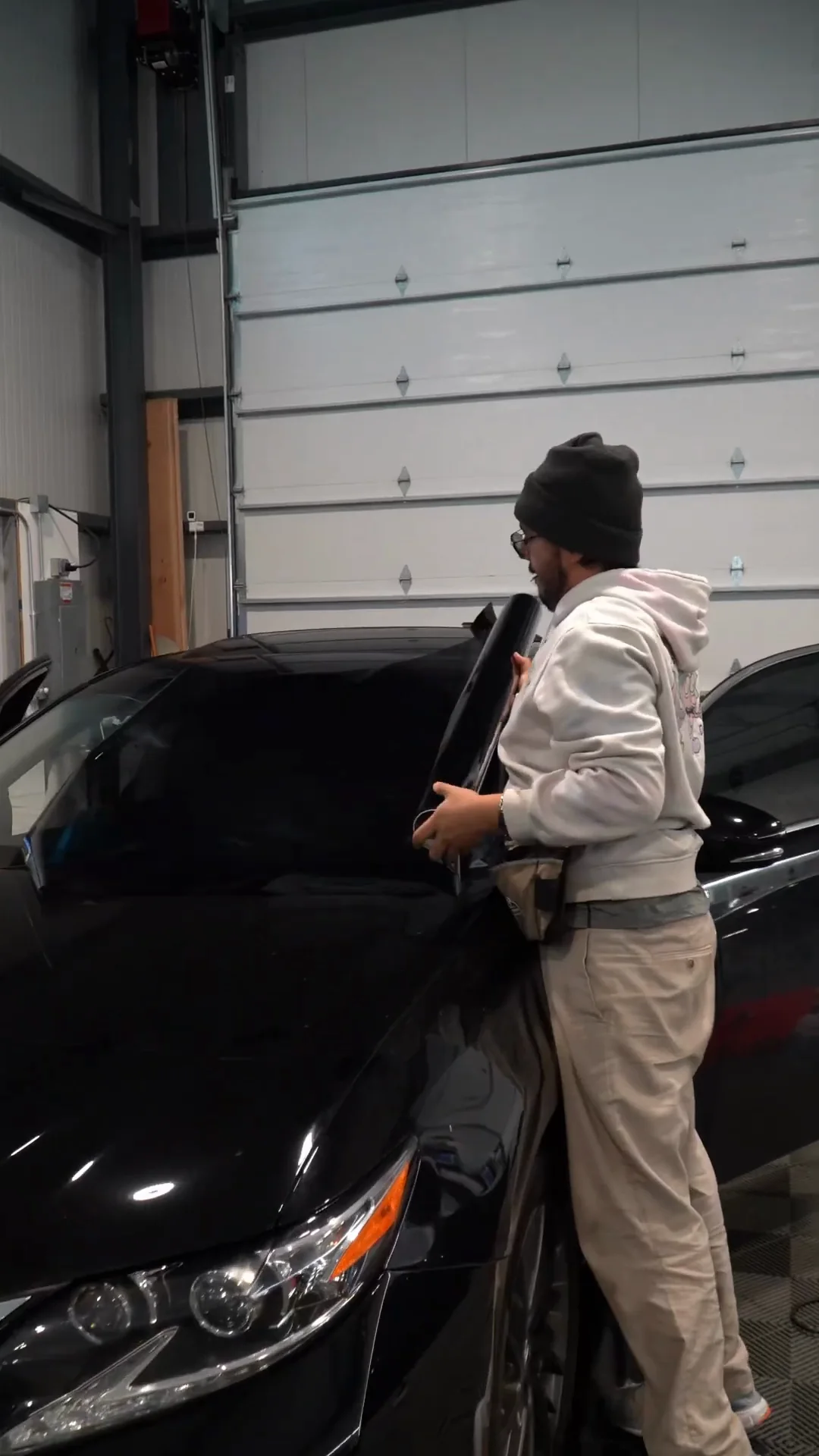 Installer at the open door of a black car in the shop