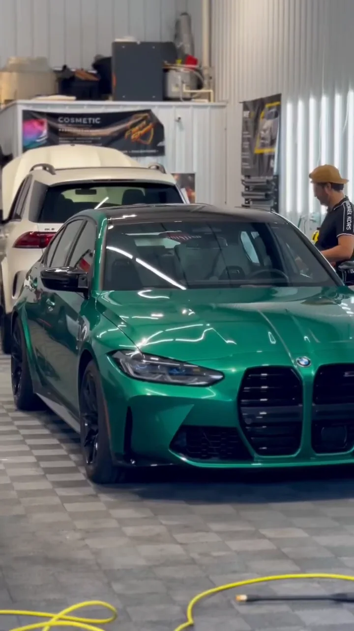 Green BMW M3 in the shop bay with installers at work behind it