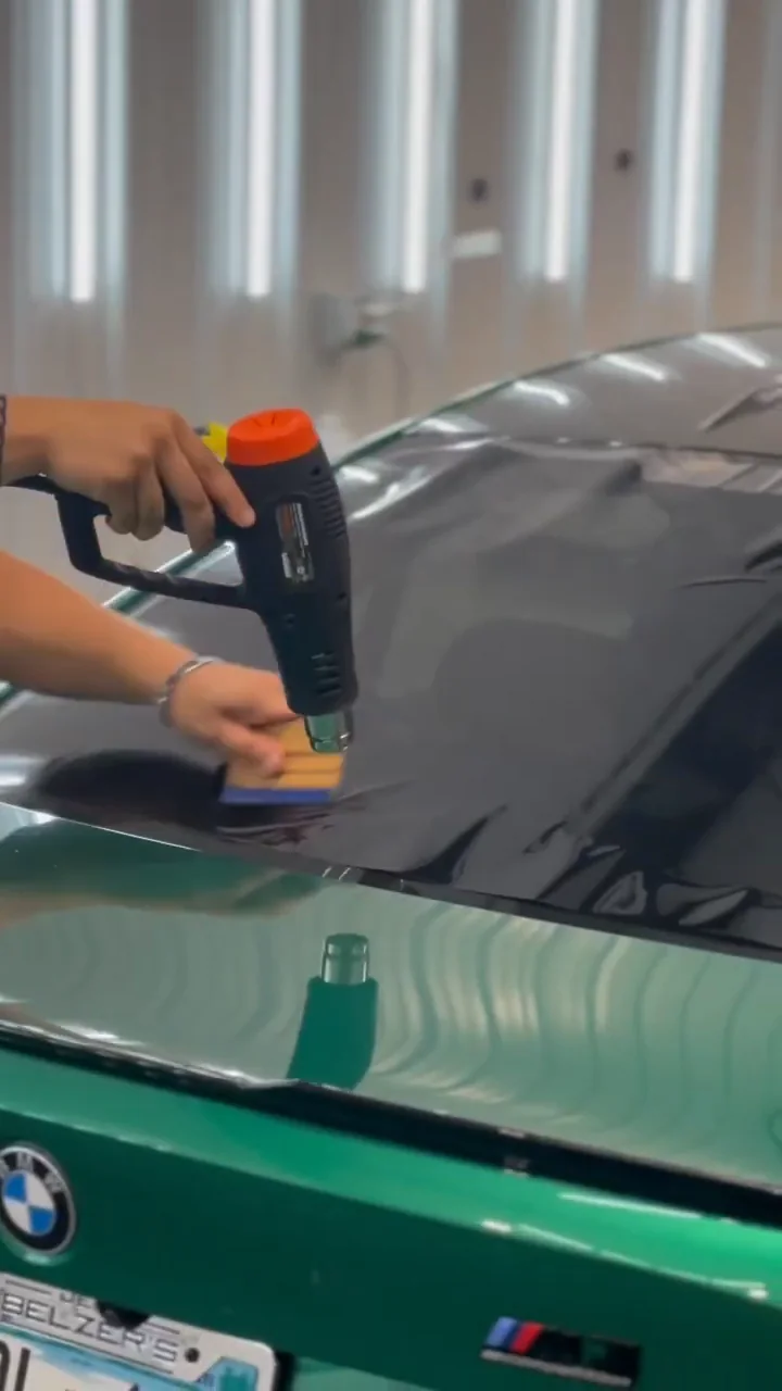 Installer heat-forming film on the rear window of a green BMW M3
