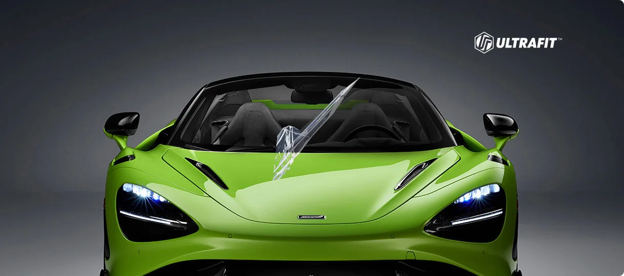 The same McLaren with a clear film peeling cleanly off the windshield in one piece